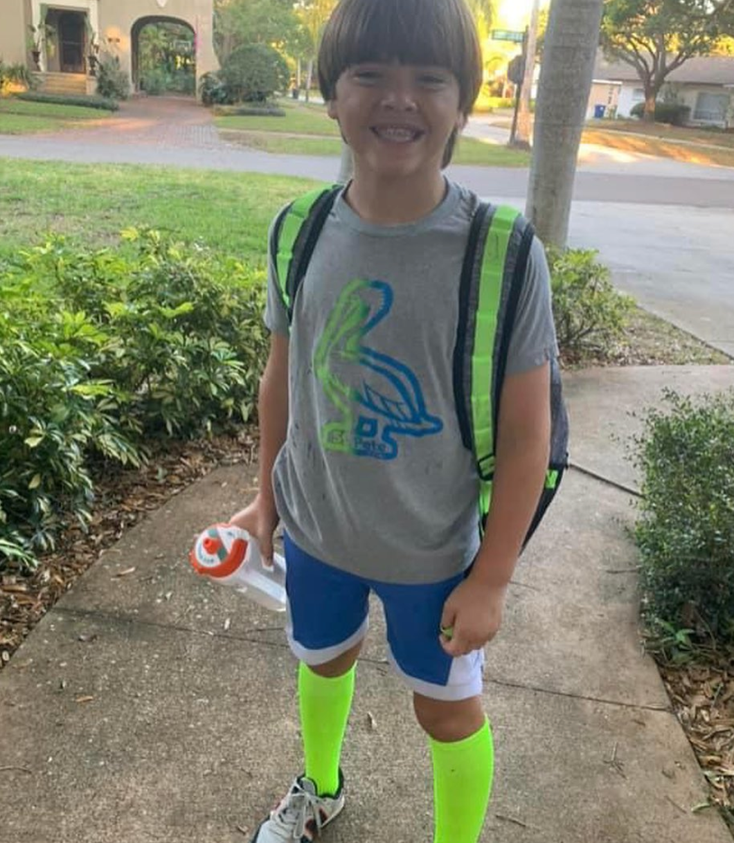 Smiling boy wearing kids St. Pete pelican t-shirt on heather grey - children's Florida bird shirt in green and blue