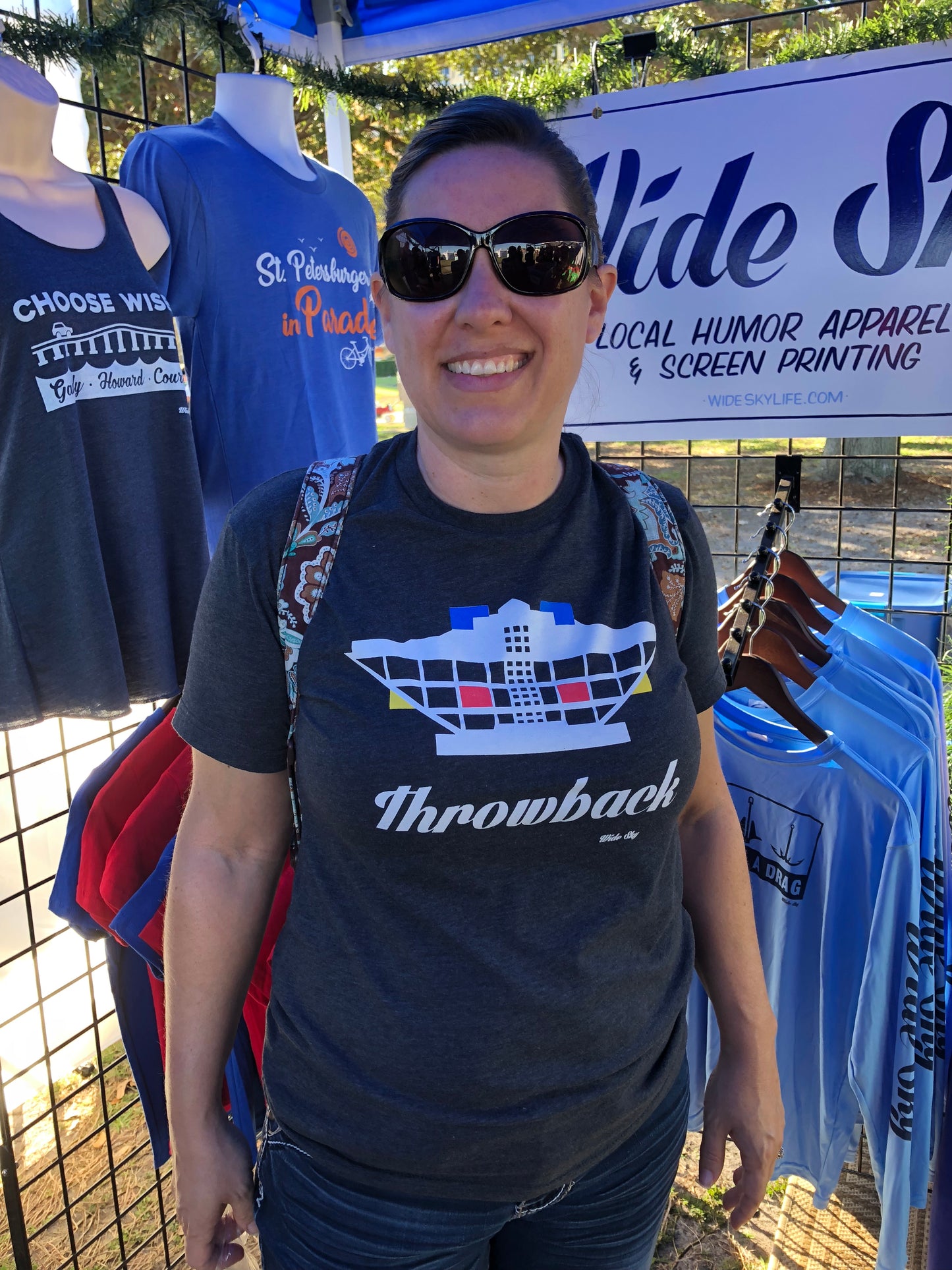 Woman standing at a festival wearing a Wide Sky designed Throwback St. Pete Pier t-shirt