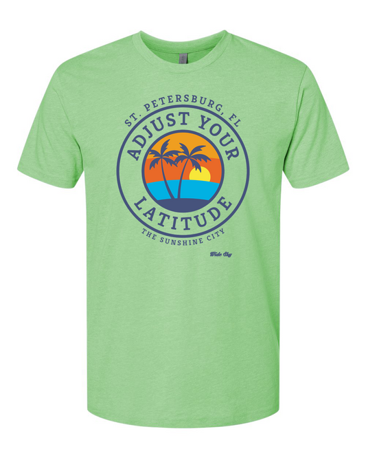 Green t-shirt with a colorful graphic design featuring palm trees and text 'St. Petersburg, FL - Adjust Your Latitude - The Sunshine City'.