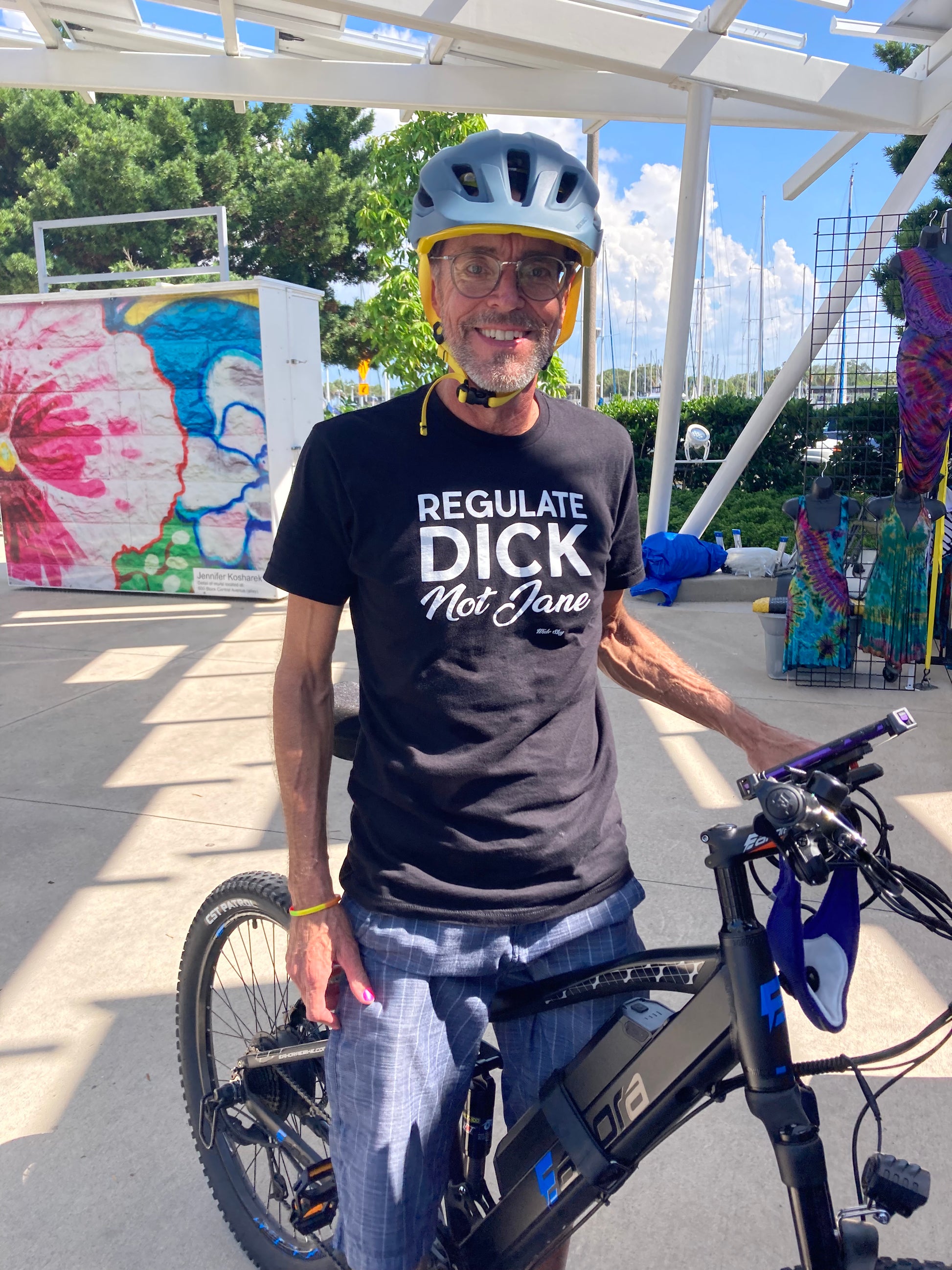 Man wearing Regulate Dick Not Jane t-shirt in black with white text - women's rights statement shirt