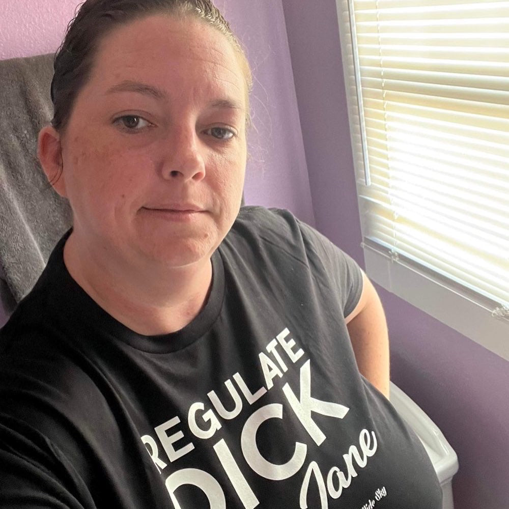 women wearing Regulate Dick Not Jane t-shirt in black with white text - women's rights statement shirt